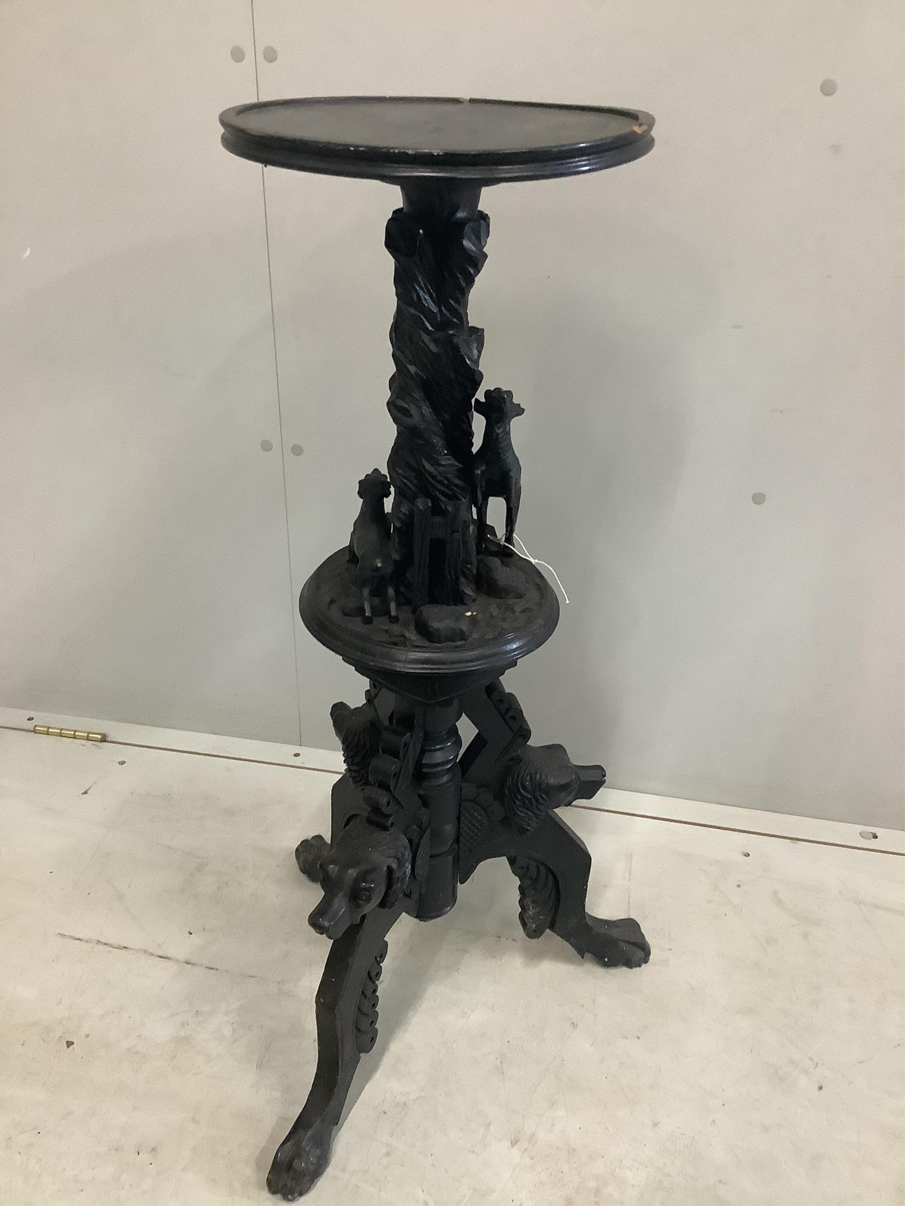 A late 19th century Black Forest ebonised wood urn stand carved with a running deer and hounds heads, height 90cm. Condition - poor, numerous losses